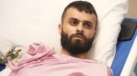 Mujahid Abadi Balas afgebeeld liggend in een ziekenhuisbed