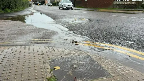 BBC Dirty water bubbling out of a manhole cover in the pavement