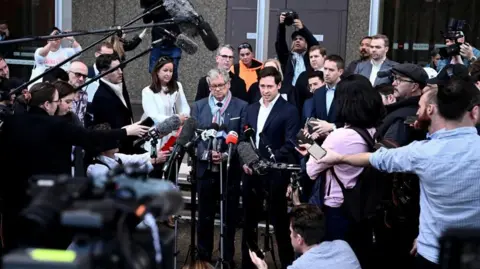 Reuters Journalists Nick McKenzie and Chris Masters give a statement outside the Federal Court, surrounded by a media pack