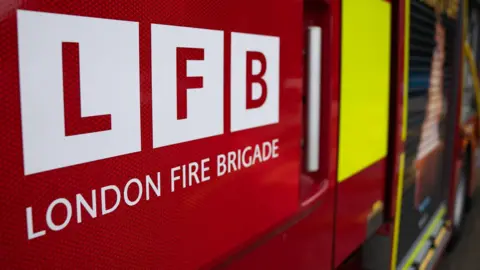 PA A close up of a red fire engine door that reads: London Fire Brigade.