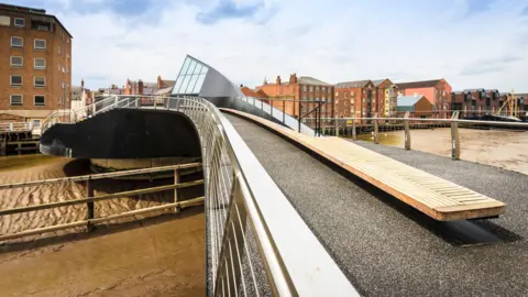 Scale Lane Bridge. The muddy banks of the river can be seen beneath it. 