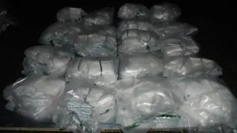 National Crime Agency A large haul of drugs all in clear bags piled on top of each other.