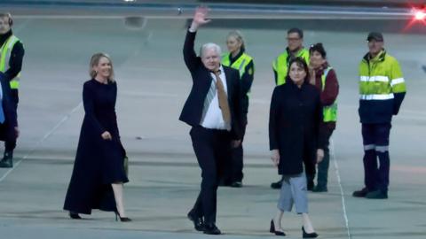 Julian Assange waving at airport as he arrives in Australia