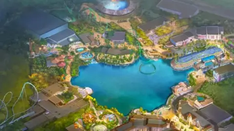 UNIVERSAL DESTINATIONS AND EXPERIENCES/COMCAST A bird's-eye artist's impression of what Universal UK will look like. There is a bright blue lake in the centre, surrounded by rides, arenas and retail units. Several rollercoasters can be seen, one of them appears to extend over the lake. It is surrounded by images of green fields.
