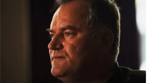 Ratko Mladić is photographed in a close up shot looking away from the camera