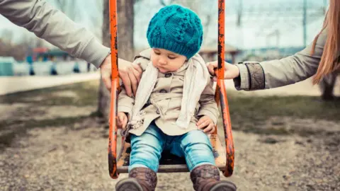 Getty Images Child on a swing in between her parents