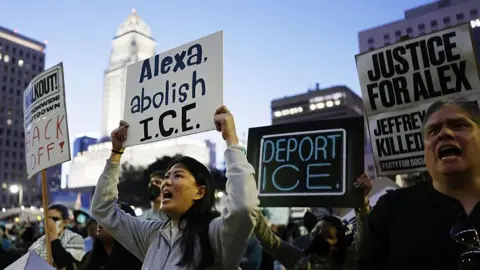 Getty Images Le persone tengono in mano cartelli con la scritta "Alexa, abolisci l'ICE", "Deportare l'ICE" E "Giustizia per Alex".