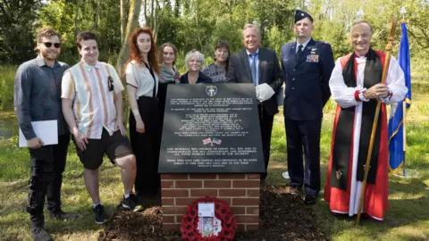 Keith Mindham The Rt Revd Dr Mike Harrison Suffragan Bishop of Dunwich, right, pictured at the memorial  with, Patrick V Hagerty, 3rd from right, son of Harold Vincent 'Hal' Hagerty who survived the crash, with other descendants along with Major William Mullins of the USAF, 2nd from right