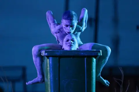 EMMANUEL ADEGBOYE / EPA Boys wearing blue body paint contort themselves into different shapes.