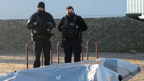 Reuters Police officers stand next to a boat after a rescue operation of migrants who tried to cross the Channel, in Berck, France January 14, 2022