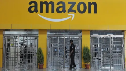 Getty Images Security guard leaving through revolving metal gates at the entrance to Amazon's fulfilment centre at Hyderabad.