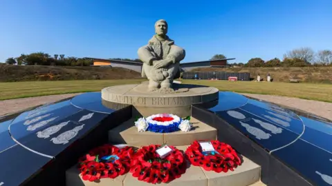 Getty Images A Second World War memorial featuring a stone statue of a solider with poppy wreaths.