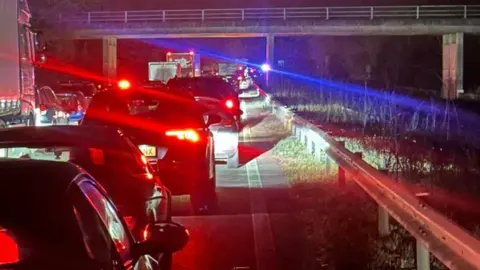 A queue of cars stuck in traffic at night. 