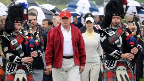 AFP S tycoon Donald Trump (C) is escorted by Scottish pipers as he officially opens his new multi-million pound Trump International Golf Links course in Aberdeenshire, Scotland, on July 10, 2012.