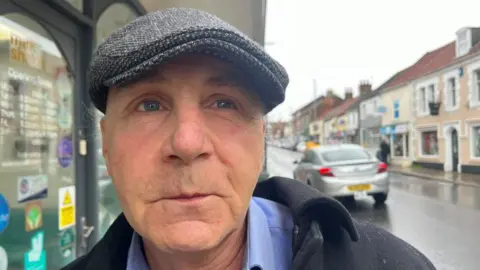 Andrew Turner/BBC Paul Fountain standing outside the East Coast Hospice charity shop in Gorleston