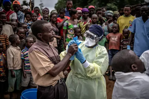 Finbarr O'Reilly for Fondation Carmignac A Red Cross burial worker shows a man how to put on protective gloves