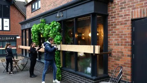 Reuters/Molly Darlington Shop staff board up shop