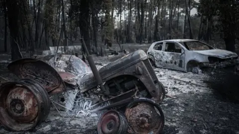 Getty Images A burnt-out tractor and car.