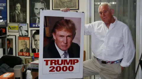 Getty Images Roger Stone holding a Trump 2000 campaign poster