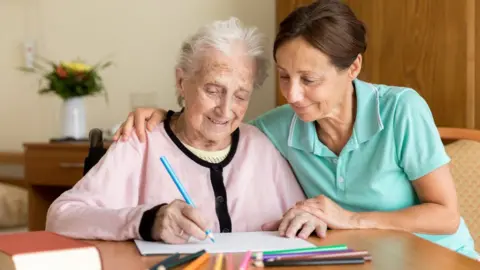 Getty Images A carer with an elderly person