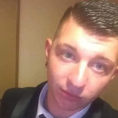 Hanratty family Ross Hanratty looking right at the camera while wearing a dark suit over a white shirt.