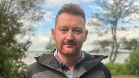 Neil Reid Dr Neil Reid has short reddish/brown hair raised up from his forehead and a reddish coloured beard