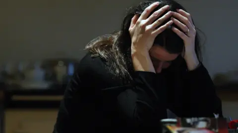 PA Media Woman with her head in hands