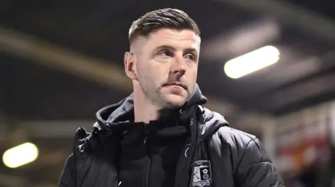 Paul Gallagher looks on from the touchline during his unsuccessful five-match spell in charge of Barrow at the start of the year