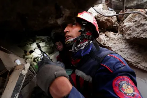 Reuters A firefighter, wearing a helmet and heavy duty coat, holds a small search camera in his hand as he searches for earthquake survivors.