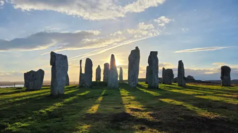 Tim Morris Standing stones casting shadows on the grass as the sunrise.