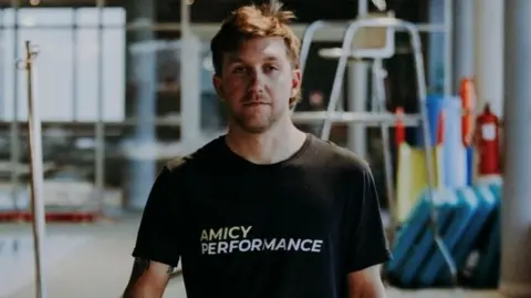 Family handout A man looking forwards at the camera wearing a black top which reads 'Amicy Performance'