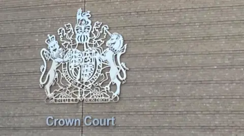 Brian Farmer/BBC Exterior grey wall of Cambridge Crown Court showing a silver coat of arms and the words "Crown Court"