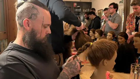 Tattooed father of two Paul Jessop gets to grips with a plait on his mannequins head. 