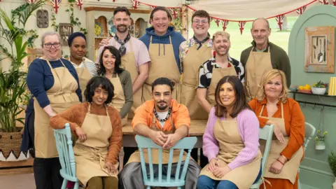 Un grupo de doce con delantales marrones en la carpa Great British Bake Off de Channel 4/Love Productions. 