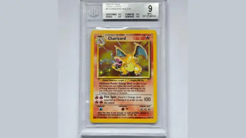 Richard Winterton Auctioneers The image shows Mr Free's rare Charizard Pokémon card which is inside a protective, clear case with a sticker detailing the BGA grade of 'mint'. The Pokémon can be seen on the card with information about the creature and its skills from the show.