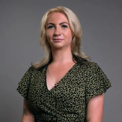 BBC Scotland Jenni, a young woman with shoulder-length, blonde hair, looks at the camera. She is wearing a green and black animal-print top. 