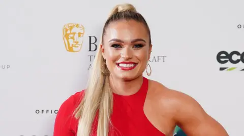Ian West/PA Wire Woman in red dress with long blonde hair.