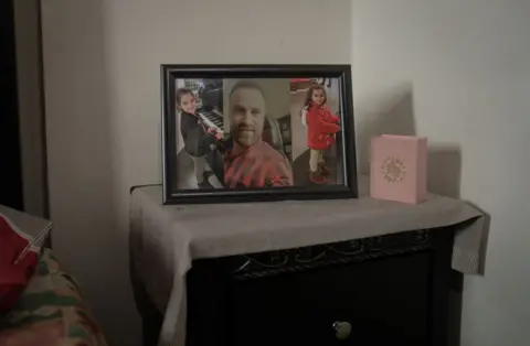 Joel Gunter/BBC Photo Rihab's husband Saeed and their two daughters Naya and Tea sit on her bedside table. (Joel Gunter/BBC)