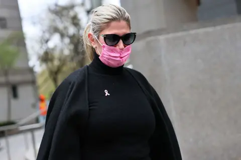 Nadine Menendez is photographed in a spotted in a pink mask, a black coat and a black turtleneck outside of court. She is also wearing black sunglasses.