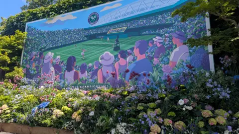 Wimbledon flowers frame a large painted canvas of people watching the tennis