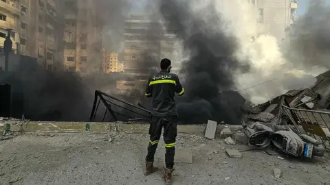 A member of the civil defence stands at the site of overnight Israeli airstrikes in the southern suburbs of Beirut