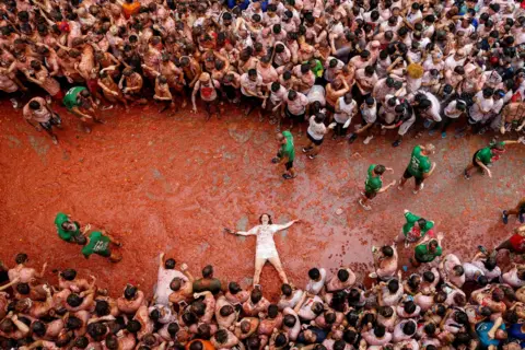 Eva Manez / Reuters A participant lies in tomato pulp 