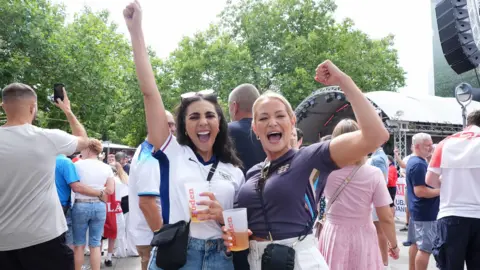 PA Two women wearing England shirts cheer with their fists pumping the air