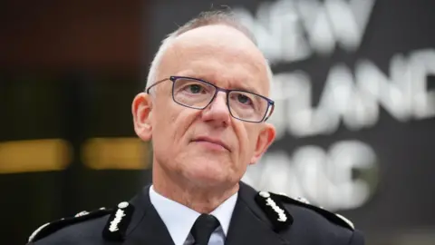 Metropolitan Police Commissioner Sir Mark Rowley stands in front of the New Scotland Yard sign