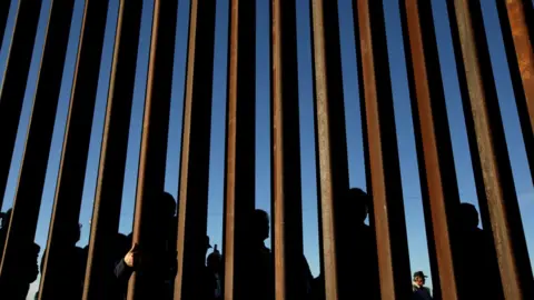 Reuters People stand at wall at the southern border