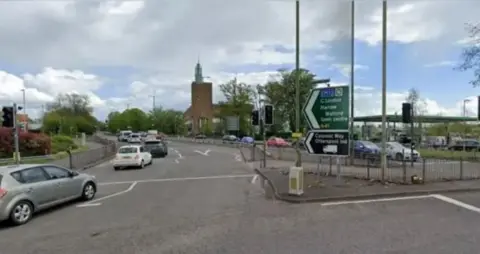 Google A modern church is in the background of a road juction with signs to London and Watford, and cars travelling around a bend.