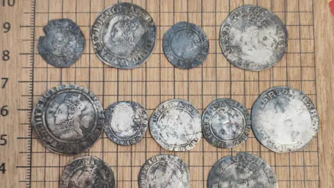 A close-up picture of a number of silver coins, some are very faded, but details are still visible on others.