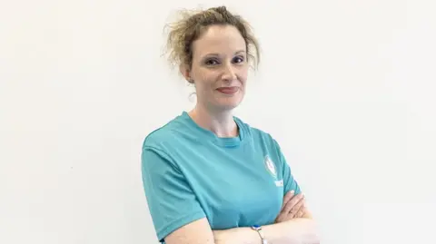 University of Brighton A woman in a blue top. Her arms are folded across her body. 