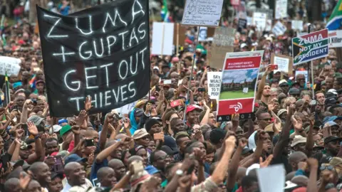 Getty Images Protester hold banner saying "Zuma and Guptas Get Out Thieves"