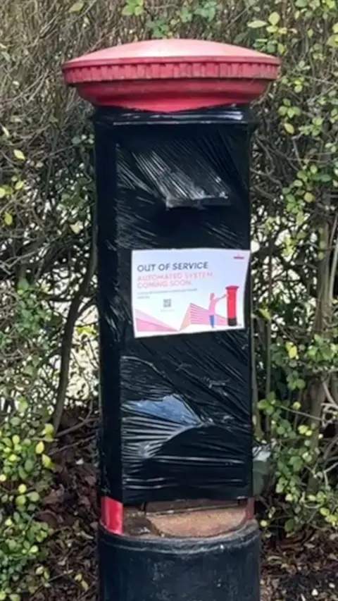 A post box covered mostly in a black bin liner apart from the very top and bottom